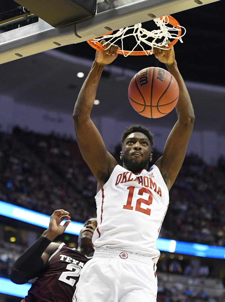 Oklahoma forward Khadeem Lattin dunks in front of Texas A&M guard Danuel House in the second half. Oklahoma moved into this weekend’s regional final with the win.