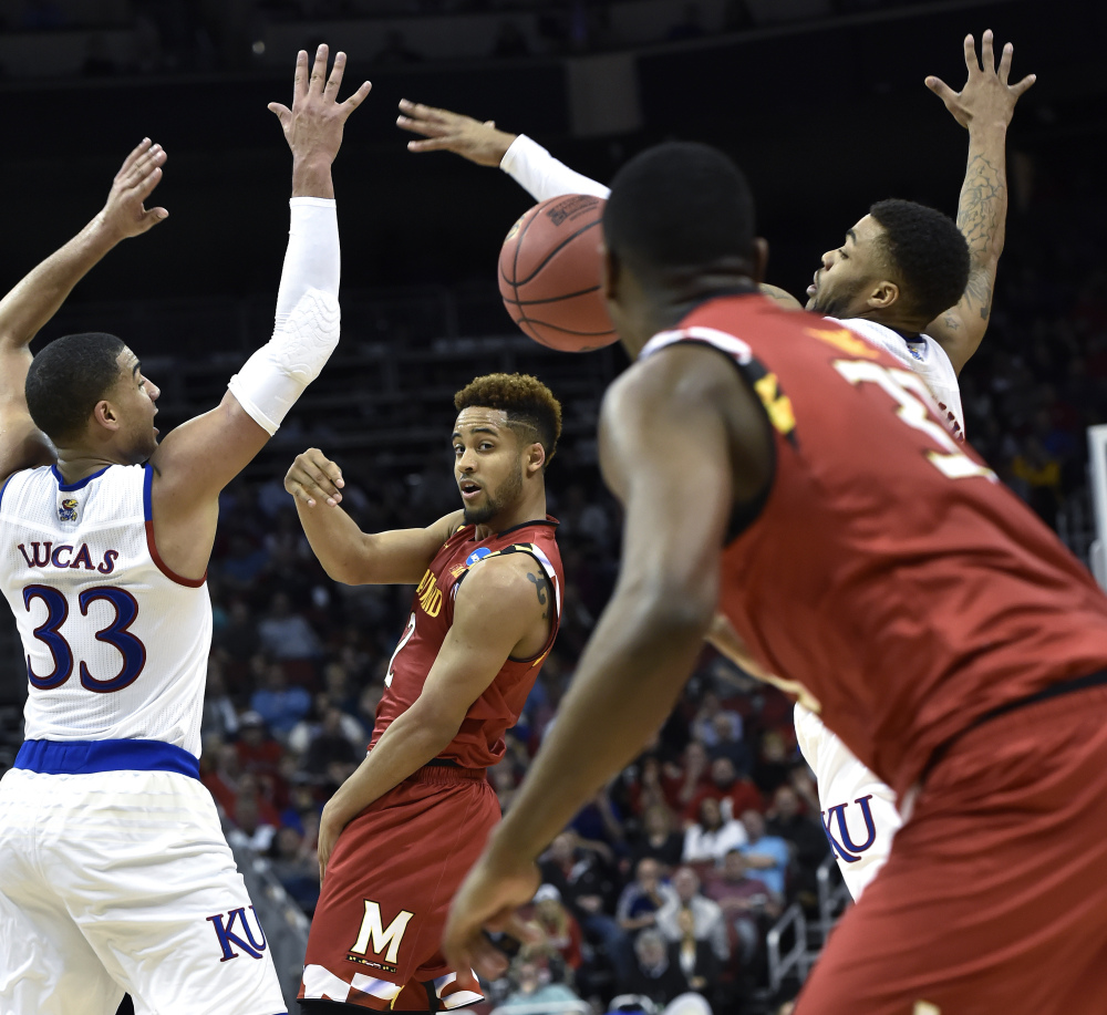 Maryland guard Melo Trimble passes the ball to a teammate between Kansas forward Landen Lucas (33) and guard Wayne Selden Jr. in the first half.