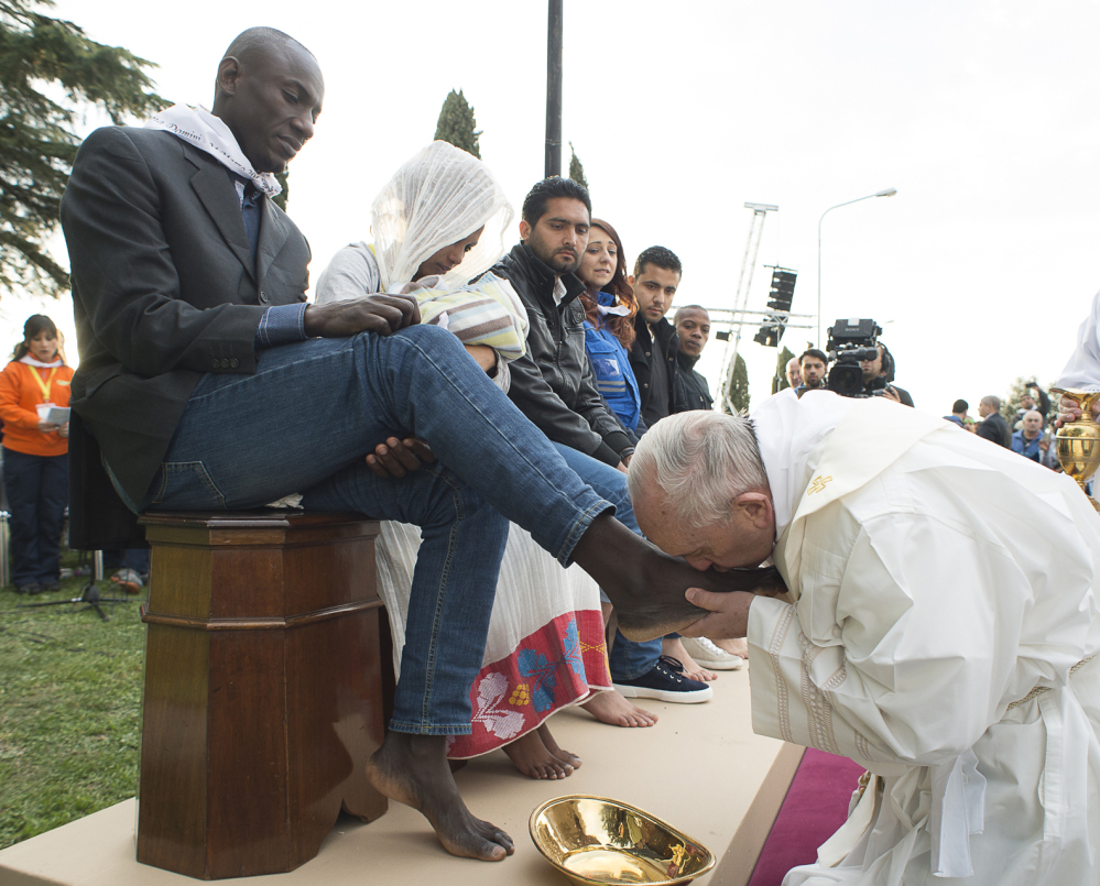 Pope Francis kisses a man’s foot during the foot-washing ritual that is also considered a gesture of brotherhood at a refugee center near Rome on Thursday.