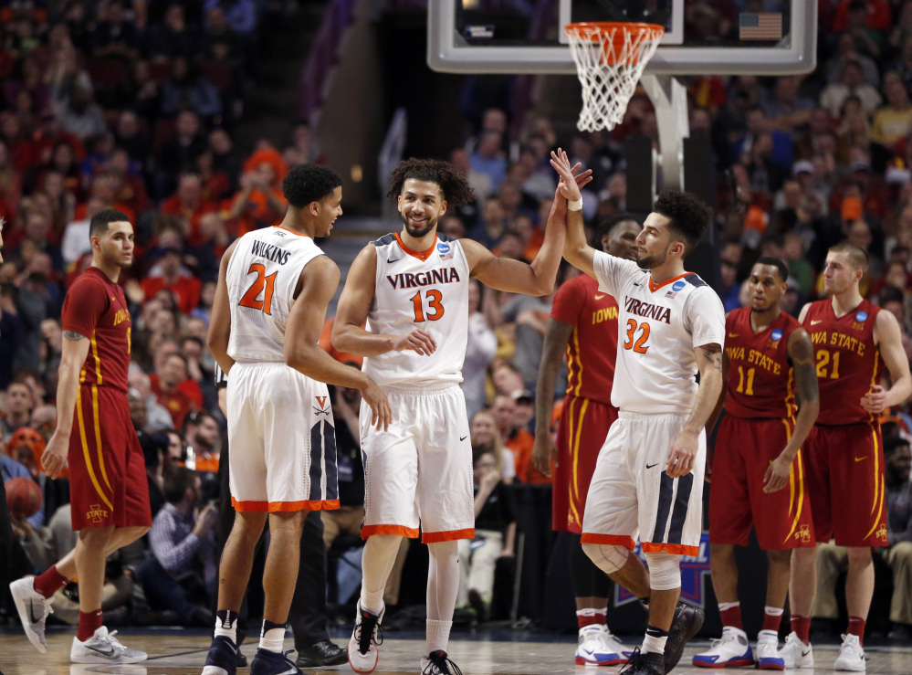 Virginia’s Anthony Gill, 13, celebrates with Isaiah Wilkins, 21, and London Perrantes after a play in the final seconds of Friday night’s Midwest Region semifinal at Chicago. Virginia beat Iowa State, 84-71.