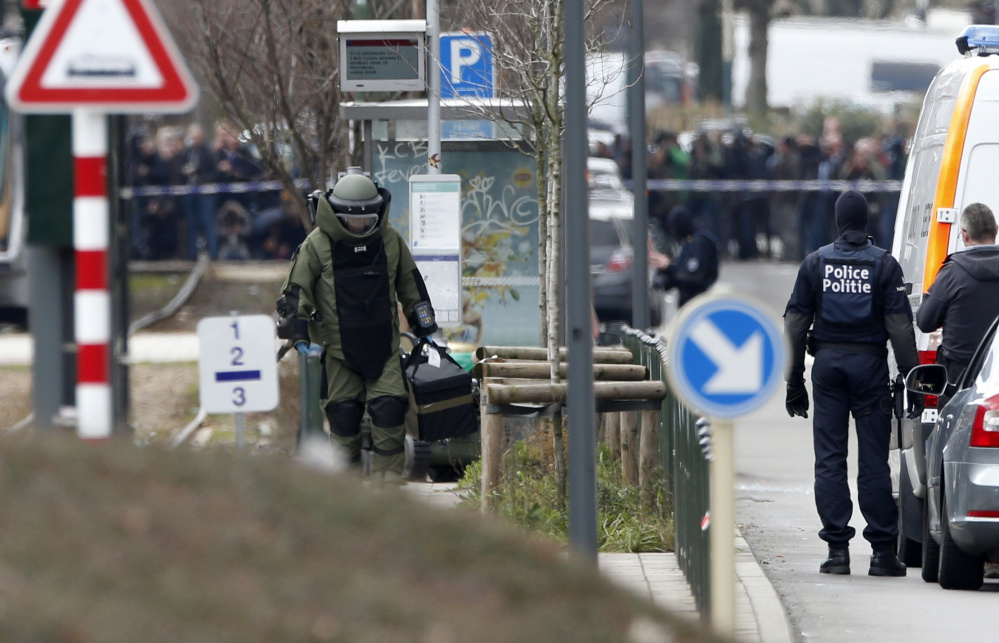 A police officer wears a bomb suit in Brussels during a day of police raids and investigations. A tram passing through the area was stopped and evacuated and police cordoned off a wide perimeter of streets.