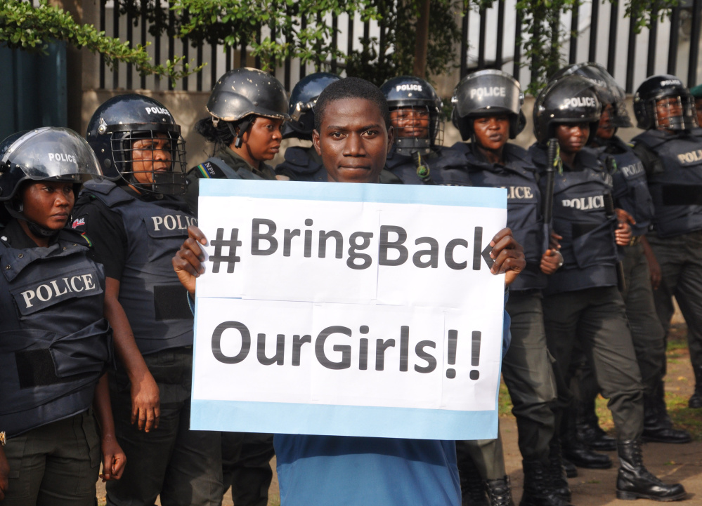 A man with a sign stands in front of police during a 2014 demonstration calling on the government to rescue the schoolgirls kidnapped by Boko Haram in Nigeria.