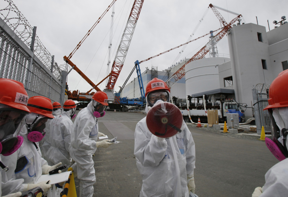 A staff member of the Tokyo Electric Power Co. speaks to journalists during a press tour in front of the No. 1 reactor at the Fukushima Dai-ichi nuclear power plant in 2014.