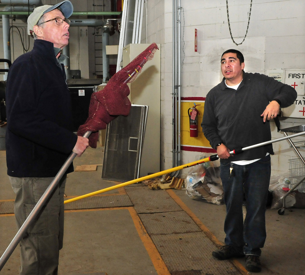 Terry Heitz, left, of Avian Haven, and Waterville Animal Control Officer Chris Martinez plan strategy Thursday to net a turkey vulture that became trapped inside the boiler building at the former Seton Hospital in Waterville.