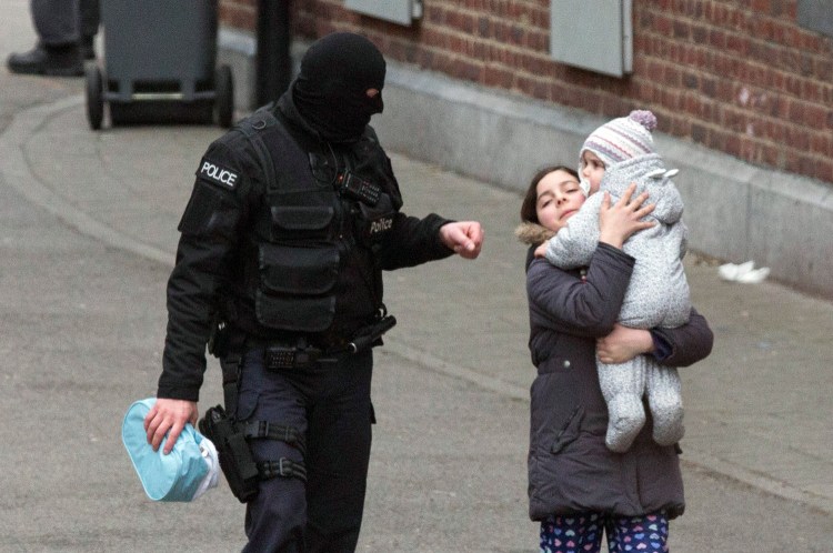 Police evacuate a woman and a small child during a police raid in the Molenbeek neighborhood of Brussels, Belgium, on Friday. Salah Abdeslam, the main fugitive sought in connection with Islamic extremist attacks in Paris in November, was arrested Friday in Belgium's capital after four months at large. 