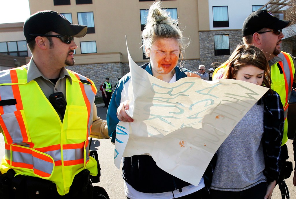 A girl who was protesting Republican presidential candidate Donald Trump at rally in Janesville, Wis., Tuesday is escorted by police after being pepper sprayed by a man during a confrontation outside the hotel where Trump was speaking. Her face was stained by the spray. Amber Arnold/Wisconsin State Journal via AP