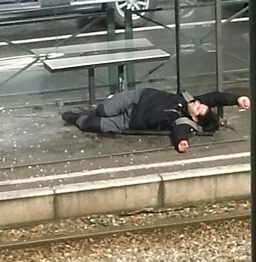 A man lies on the platform at a tram stop in Brussels, Belgium, on Friday, after being injured during a police raid. 