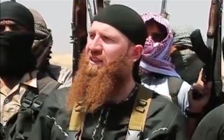 This image made from undated video posted by the Islamic Stateshows Omar al-Shishani among a group of fighters as they declare the elimination of the border between Iraq and Syria. Via AP