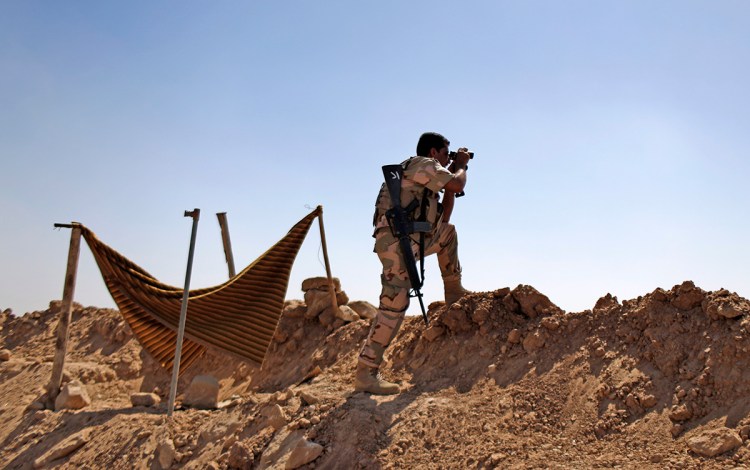 A Kurdish Peshmerga fighter checks on Islamic State group's positions on the outskirts of Makhmour, about 180 miles north of Baghdad, in this September 2014 photo. Although Kurdish forces have pushed the militants out, Makhmour still has the feel of a warzone, and many residents have stayed away. The Associated Press
