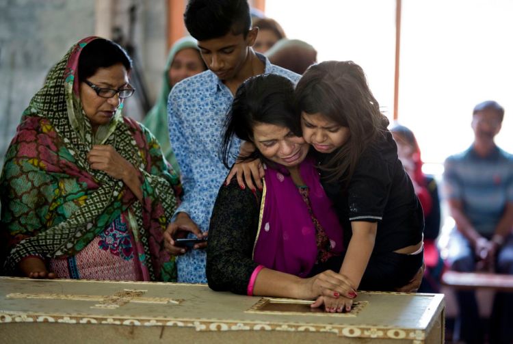 A Pakistani Christian mother looks at her son as she holds her daughter at his funeral in Lahore, Pakistan, Monday. The death toll from a massive suicide bombing targeting Christians rose on Monday as the country started observing a three-day mourning period following the attack.The Associated Press