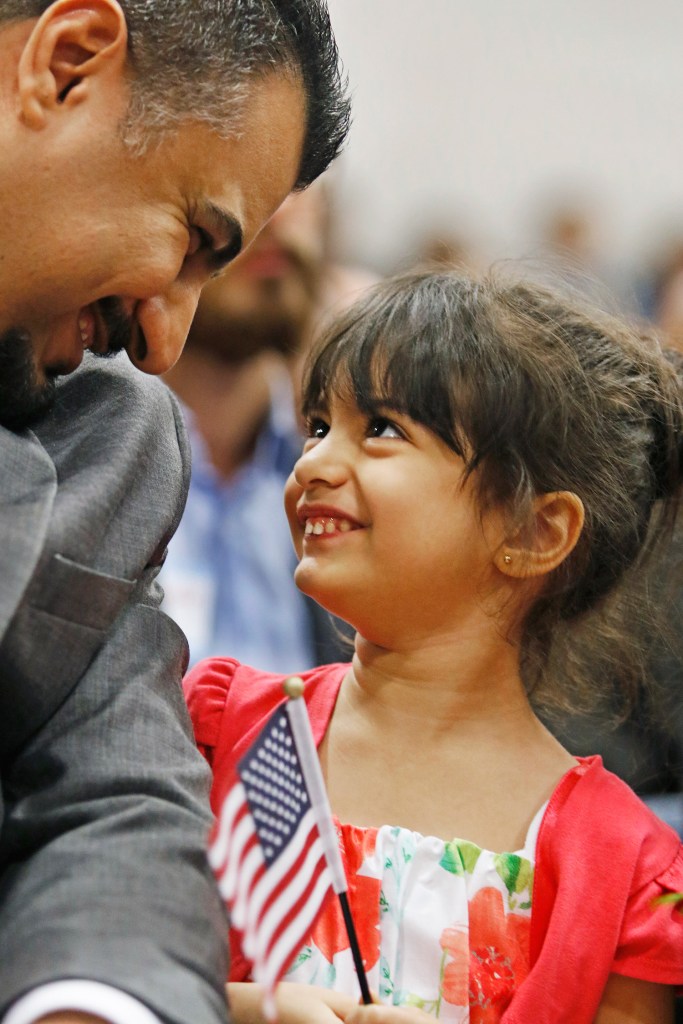 Sama Alziadi, 4, and her father, Tariq Alziadi, both of Sanford, who came to this country from Iraq, wait to be sworn in during a naturalization ceremony at Lyman Moore Middle School in Portland on April 8.