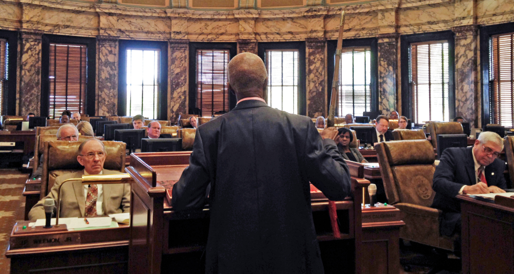 Sen. Hillman Frazier, D-Jackson, brandishes a sheathed sword Tuesday, March 29, 2016, during debate over House Bill 786, at the Capitol in Jackson, Miss. Frazier opposed the bill, which would grant immunity to trained church security teams that shoot people trying to commit violent crimes. Frazier said the bill went against Christian teaching, recounting the story of Jesus healing a servant of a high priest after a disciple cut off the servant's ear with a sword. (AP Photo/Jeff Amy)
