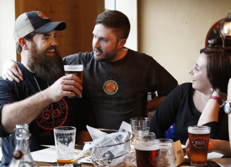 Andy Geaghan of Geaghan Brothers Brewing, left, Chris Bougie and Lisa Sturgeon raise a glass at the Little Tap House after the summit Friday.