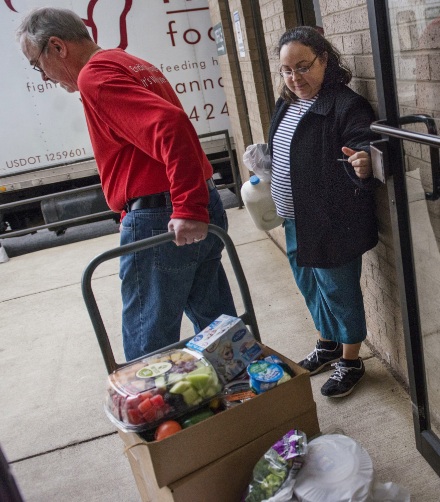 Rosalba Diaz holds the door for Dean Swanson on Thursday at the Manna Food Center in Gaithersburg, Md. As of Friday, recipients of food stamps in 22 states faced a work mandate.
