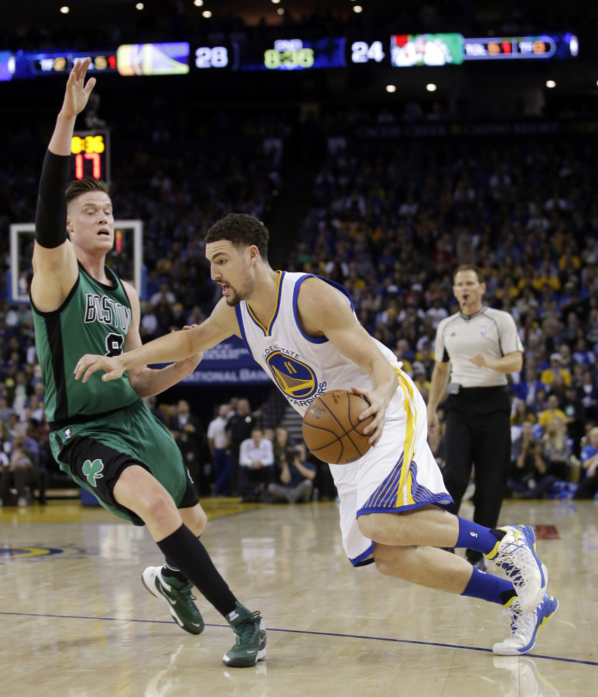 Golden State's Klay Thompson, left, dribbles to the basket while being defended by Boston's Jonas Jerebko during the Celtics' 109-106 loss Friday night. It was the Warriors first loss at home in 55 regular season games.