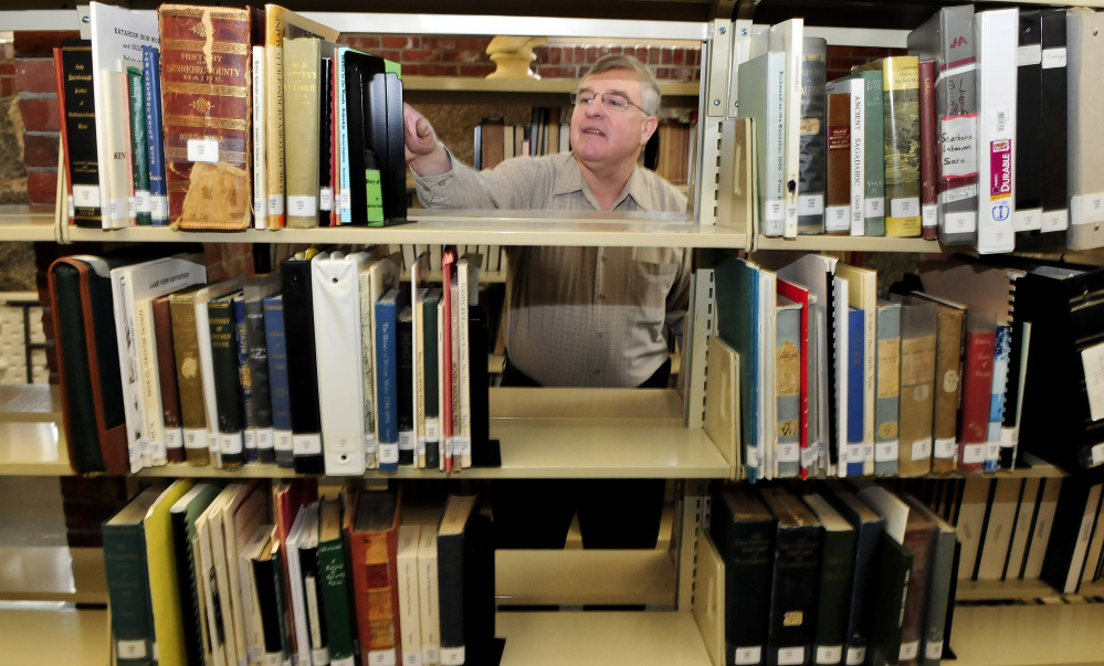Dale Jandreau, librarian at Skowhegan Free Public Library, selects a book of documents on area families Wednesday in the library's new genealogy section.