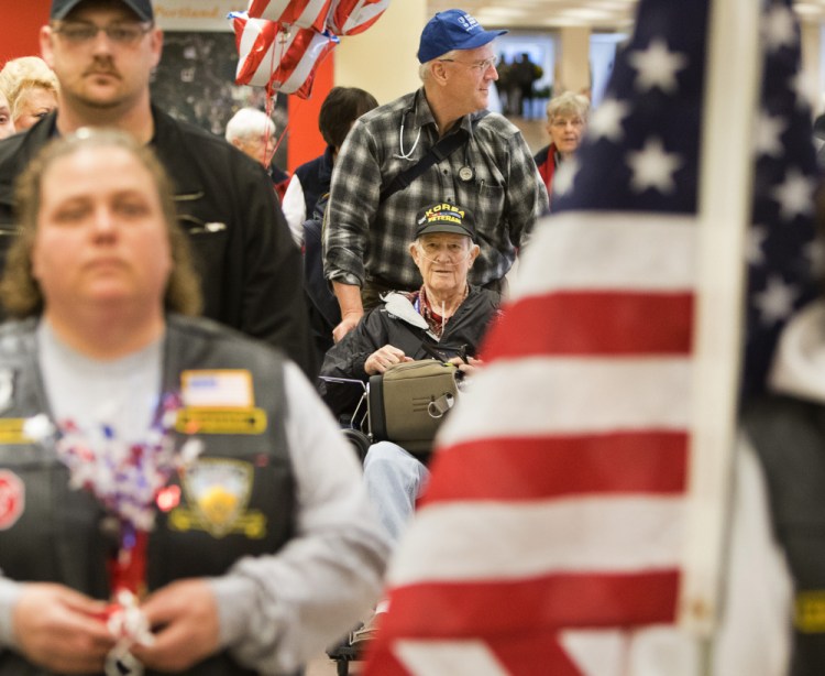 Korean War veteran George McCann, 81, is wheeled by Earl Morse during a processional through the Portland International Jetport on Sunday after returning from his Honor Flight to Washington, D.C.