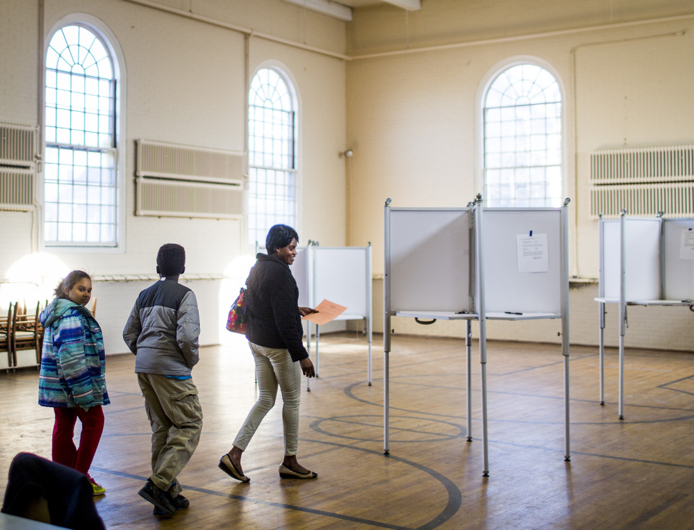 Angelina Wani, 9, and her brother Remijo, 11, follow their mother Betty Lasu into the Woodfords Congregational Church on Tuesday while she votes on a referendum to pay for renovations at Hall School.