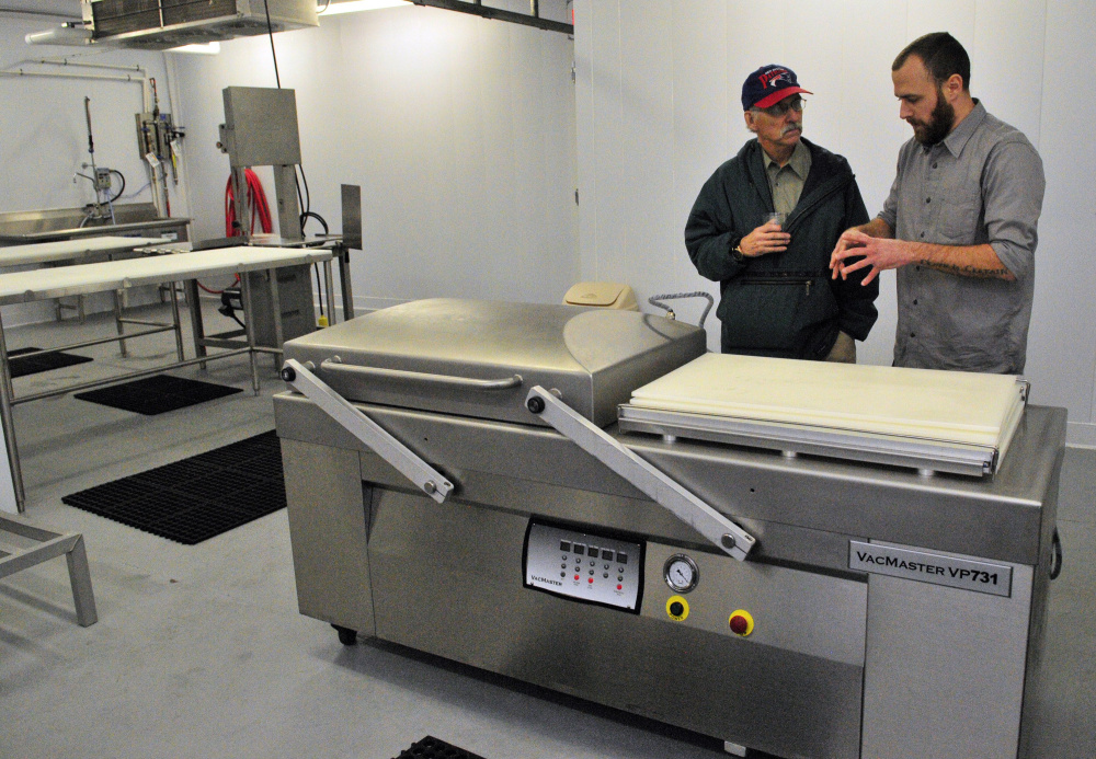City councilor Phil Hart, left, talks about a cryovac packaging machine with Eben Harrington, the hazard analysis and critical control points manager, during a tour of the Central Maine Meats processing facility in Gardiner.