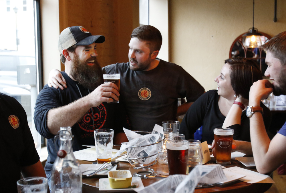 Andy Geaghan of Bangor's Geaghan Brothers Brewing, left, Chris Bougie and Lisa Sturgeon raise a glass at the Little Tap House after the inaugural New England Brew Summit in Portland last Friday. The high quality of Maine beers is drawing aficionados from around the world.