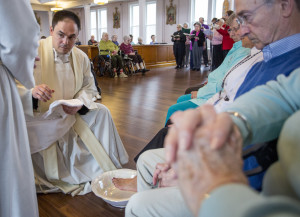 The Rev. Paul Dumais says Mass (above) and the washes the feet of worshippers (below) on Holy Thursday at the d'Youville Pavillion at St. Mary's Hospital in Lewiston.