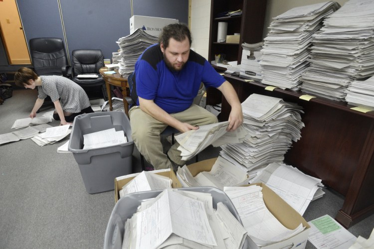 Staff members and volunteers for the marijuana legalization campaign sort petitions at their office in Falmouth in January. A court ruling Friday revives the campaign to put the question on the November ballot.