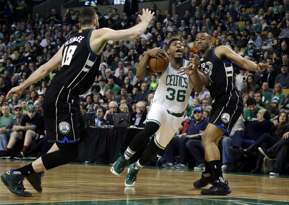 Celtics guard Marcus Smart drives between Bucks center Miles Plumlee, 18, and forward Jabari Parker in the first half Friday night in Boston.