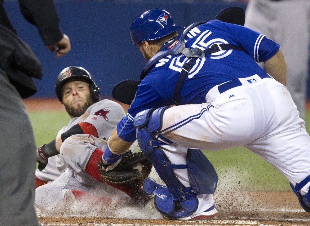 Boston's Dustin Pedroia is out at home plate with the tag from Toronto catcher Russell Martin during third inning of the Blue Jays' 3-0 win Sunday in Toronto.