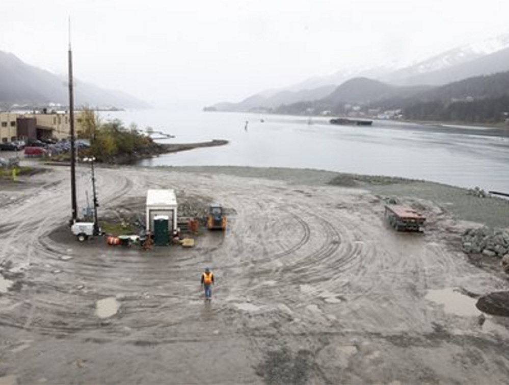 A worker walks on the site that will soon host a life-sized whale sculpture and bridge park along a channel in Juneau, Alaska, a project that led a cruise ship group to sue the city.