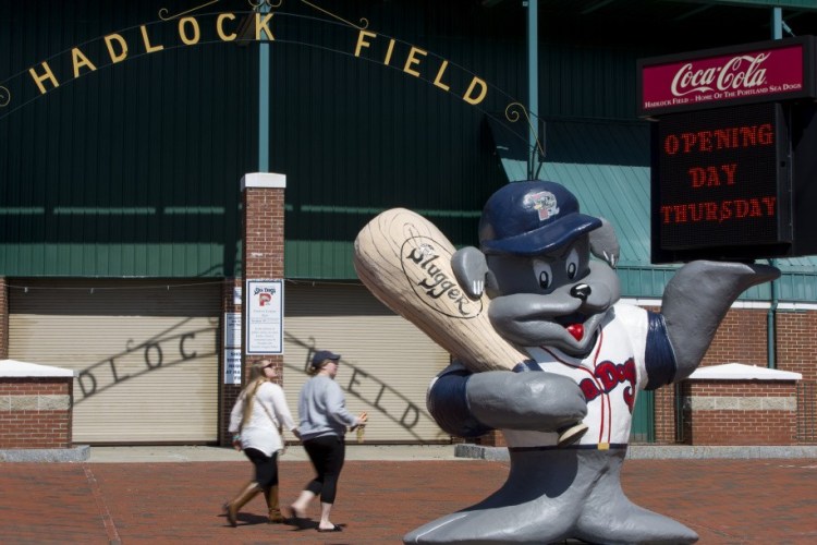 A sign held by Slugger announces opening day at Hadlock Field, which now has metal detectors. State law prohibits firearms in venues that hold liquor licenses.