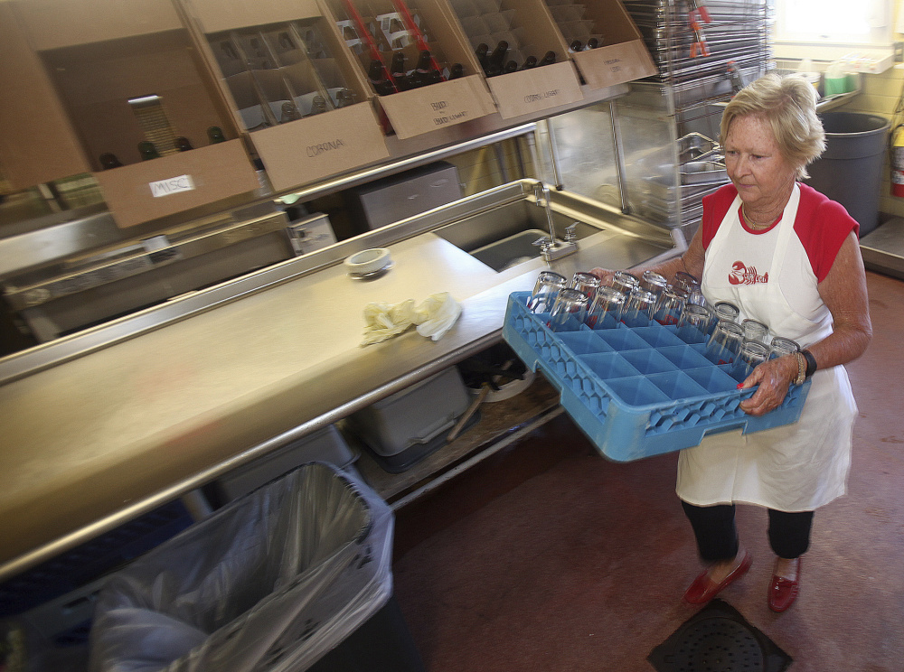 Lobster Claw Restaurant co-owner Marylou Berig, 73, puts away clean glasses after washing them in the morning before the restaurant opens. The Berigs, like many of Cape Cod's seasonal business owners, are dealing with the fallout from a federal government delay in processing H-2B visas for seasonal non-immigrant workers.