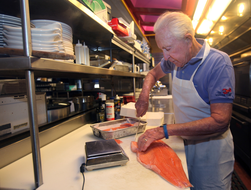 Lobster Claw Restaurant co-owner Don Berig, 76, cuts up some salmon to prepare for the 11:30 a.m. opening. Putting in 15-hour days as cook and cleaner is not what he expected to be doing at this point in his life, but he and his wife, Marylou, are on the front lines at the Lobster Claw until the restaurant's seasonal workforce arrives.