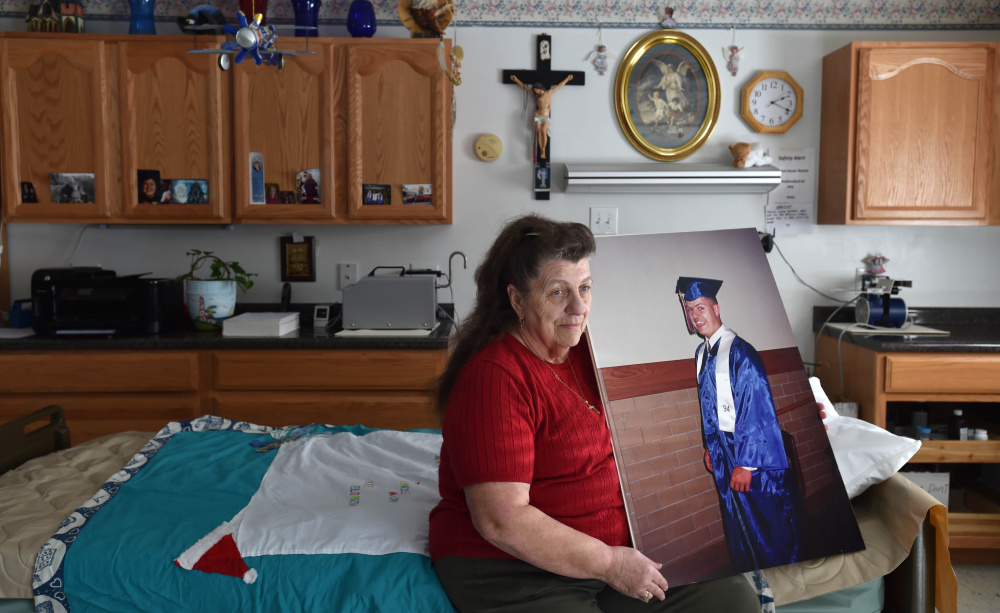 Angela Hinck last week sits on her son Aaron Mullen's bed with a graduation picture of him from 1994. Mullen was shot in the head months after graduating from high school. He lived in a coma for more than 21 years until he died on April 9.