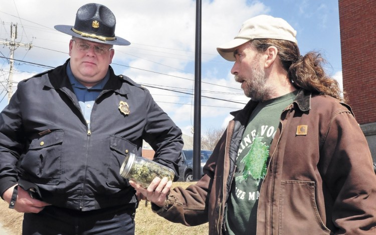 Marijuana legalization advocate Donny Christen shows a jar of marijuana to Skowhegan Deputy Police Chief Dan Summers during the Patriot's Day smoke-in on the steps of the Somerset County Courthouse in 2013. The annual smoke-in is his continued effort to draw attention to legalize marijuana. Christen is a medical marijuana patient and can legally possess the drug.