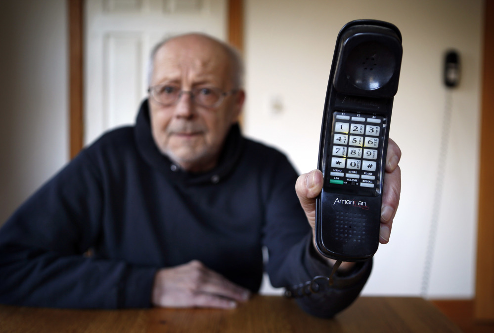 Peter Froehlich holds the landline telephone he uses at his rural home in Whitefield. Across the country, telecom companies are lobbying lawmakers to be released from their mandate of providing service to every home.