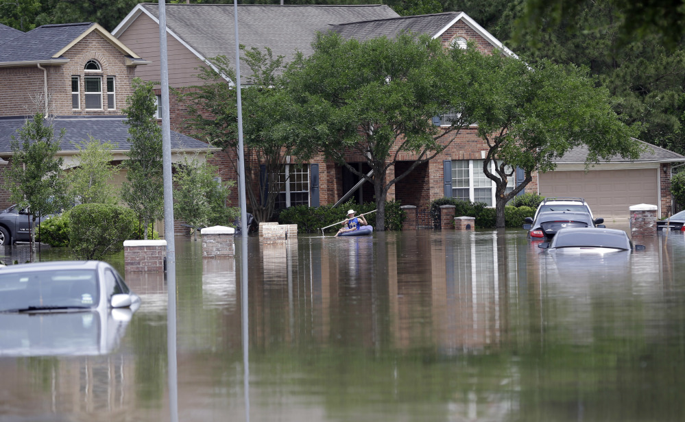 A person paddles through a flooded neighborhood, Tuesday, April 19, 2016, in Spring, Texas. Storms have dumped more than a foot of rain in the Houston area, flooding dozens of neighborhoods. (AP Photo/David J. Phillip)