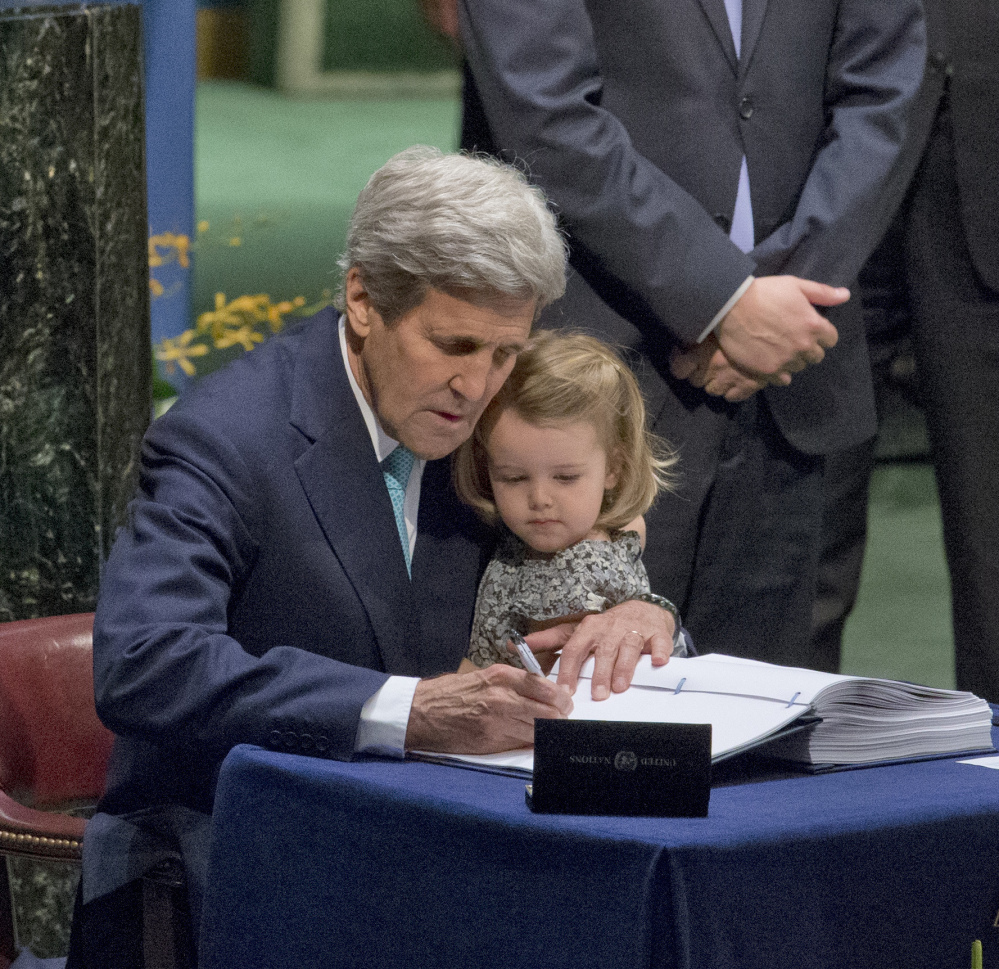 U.S. Secretary of State John Kerry holds his granddaughter as he signs the Paris Agreement on climate change Friday at the United Nations in New York.