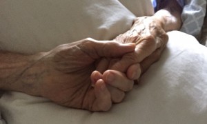 At left, Robert and Lucille Robinson hold hands Monday in their beds at a Falmouth assisted living facility.