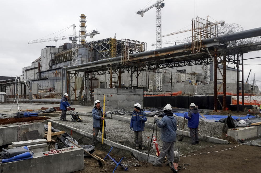 Workers labor to build a vast new structure to enclose the sarcophagus, in background, that covers the damaged fourth reactor at the Chernobyl Nuclear Power Station in Ukraine. Tons of radioactive waste have yet to be removed from the site.