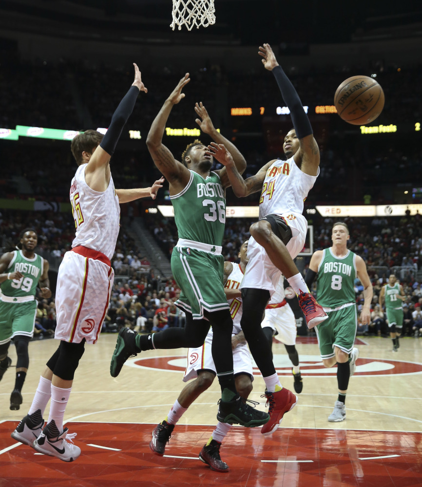 Celtics guard Marcus Smart loses control of the ball as he tries to drive between Atlanta Hawks' Kyle Korver , left, and Kent Bazemore. 