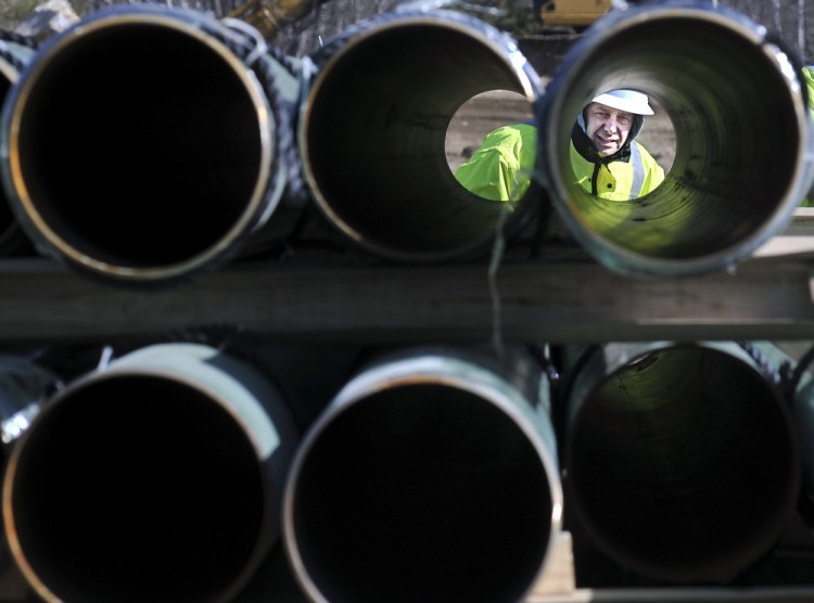 A worker from Maine Natural Gas peers through pipes to be installed at a natural gas expansion project in Windsor in 2013. The Public Utilities Commission starts hearings Thursday on a plan to increase Maine's natural gas capacity and potentially lower electricity bills by having customers pay up to $75 million a year to ensure adequate supply of the fuel. One key question: Is Maine still at risk of more shortage-driven price spikes?