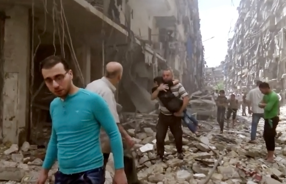 In this image made from video and posted online from Validated UGC, a man carries a child after airstrikes hit Aleppo, Syria, on Thursday.