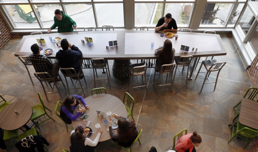 University of New Hampshire students have lunch at a $17,570 custom-made chef's table, shown at top, in a campus dining hall on Friday in Durham, N.H.