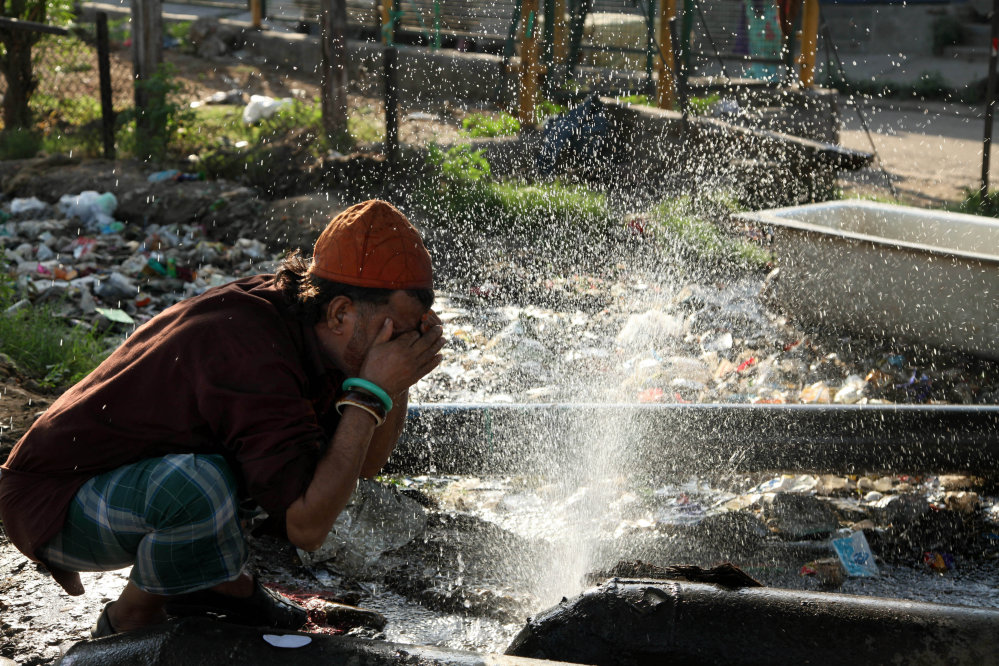 An Indian village man sprinkles water from a broken pipe onto his face in a village in Samba district, some 40 kilometres (25 miles) from Jammu, India, Friday, April 29, 2016. Much of India is reeling under a weekslong heat wave and severe drought conditions that have decimated crops, killed livestock and left at least 330 million Indians without enough water for their daily needs. (AP Photo/Channi Anand)