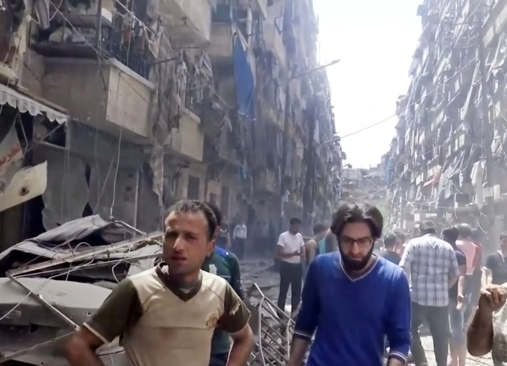 Men look at damaged buildings after airstrikes hit the rebel-held part of the contested city of Aleppo, Syria, on Thursday, killing more than a dozen people.