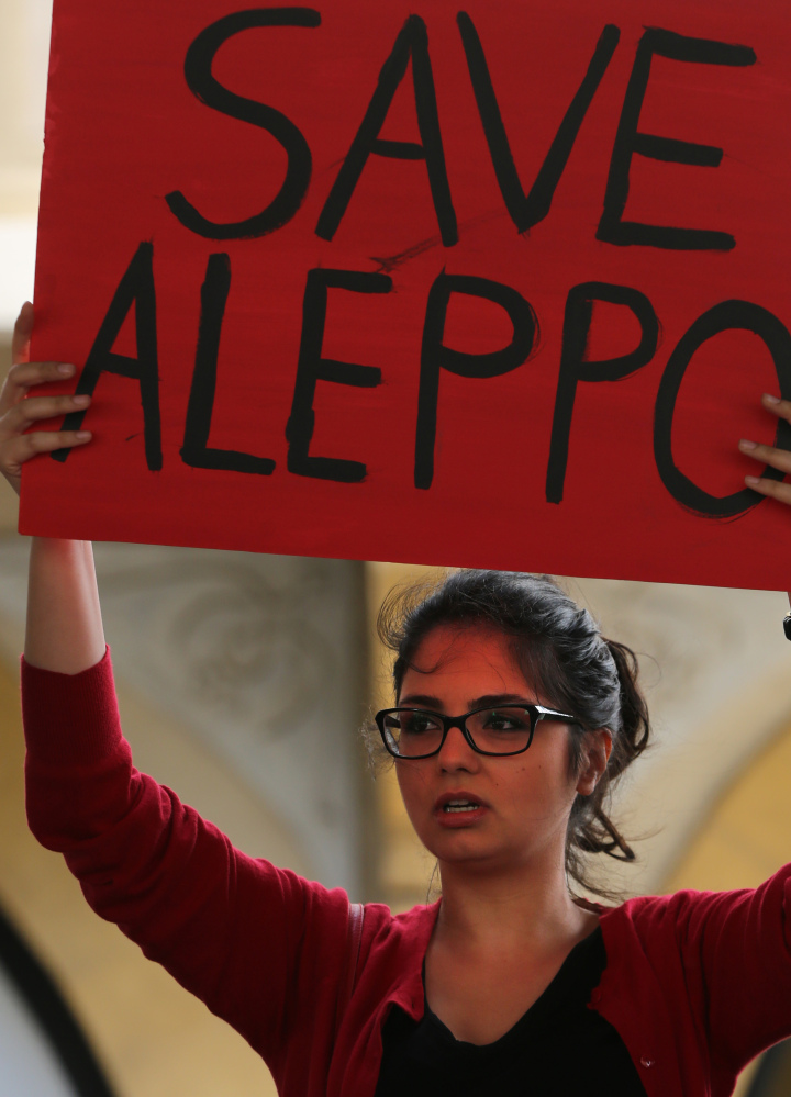 A protester holds up a placard during a protest in downtown Beirut, Lebanon, Saturday, April 30, 2016, against Syrian President Bashar Assad's military operations against areas held by insurgents around the country, mostly in the northern city of Aleppo that has been the main point of violence. (AP Photo/Bilal Hussein)
