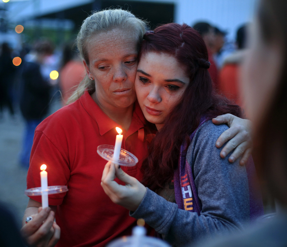 Amber Cassell, 16, right, gets a hug from Margaret Williams as they hold candles during the vigil at the Pike County Fairgrounds in Piketon, Ohio, on Friday.