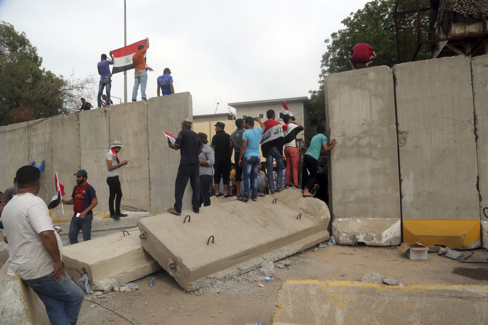 Supporters of Shiite cleric Muqtada al-Sadr walk over the blast walls surrounding Baghdad's highly fortified Green Zone on Saturday. Dozens of protesters stormed the Parliament building, carrying Iraqi flags and chanting against the government.
