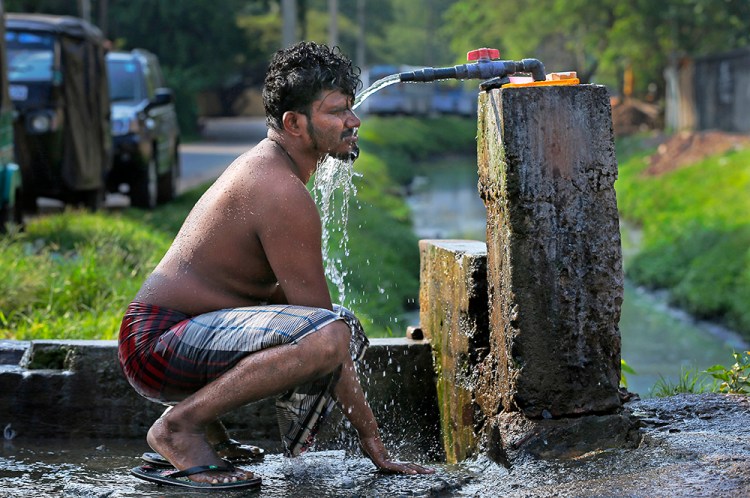 A Sri Lankan man takes a bath from a roadside tap to cool himself off from the rising temperature in Colombo, Sri Lanka. Earth’s record heat streak has hit a record 11 months. The Associated Press