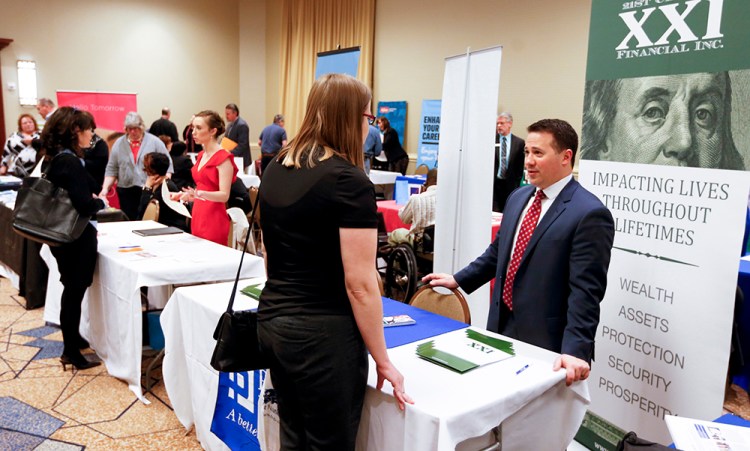 Company representatives speak with job seekers at a job fair in Pittsburgh recently. First-time claims for jobless benefits have held below 300,000 – a level typically associated with robust labor conditions – for 59 consecutive weeks. The Associated Press